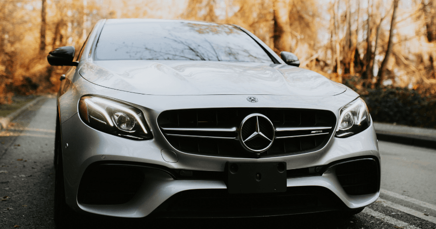 Front view of a silver Mercedes-Benz E-Class AMG parked on a tree-lined road