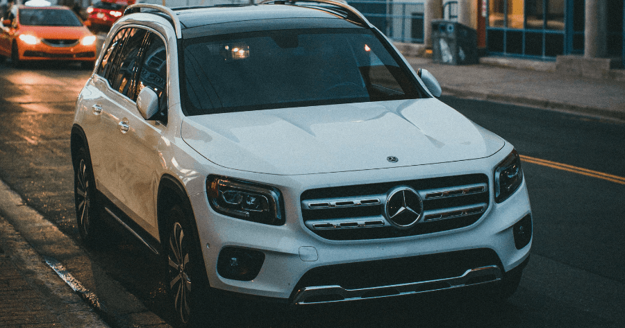 Front view of a white Mercedes-Benz GLB parked on a city street at dusk