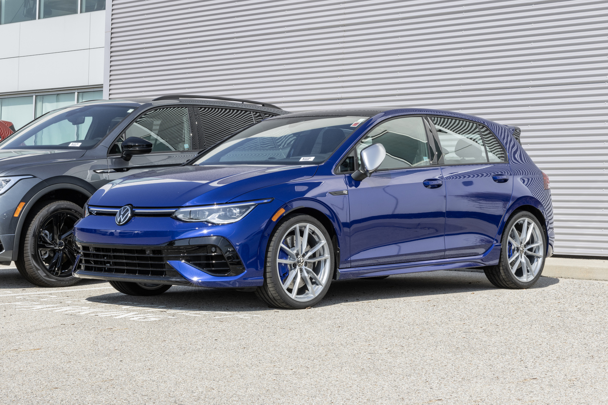 Blue Volkswagen Golf R hatchback parked outside a building on a sunny day.