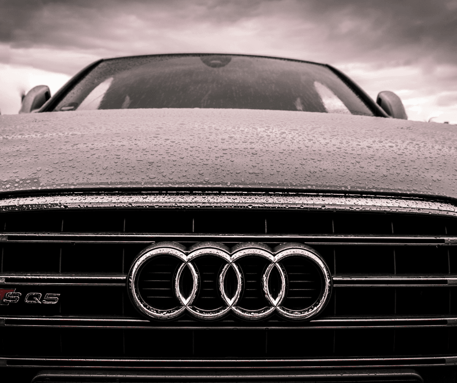 Dramatic black and white close-up of Audi SQ5 grille with four-ring badge and water droplets