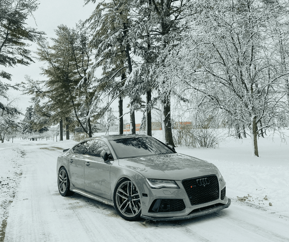 Silver Audi RS7 on tree-lined winter road with snow-covered branches