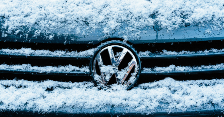 Snow packed into the grille of a Volkswagen around the chrome VW emblem