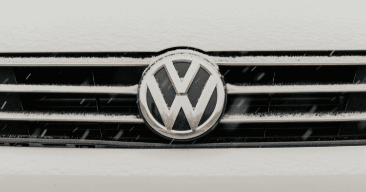 Close-up of a Volkswagen emblem and grille dusted with fresh snow