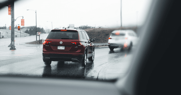 Rear view of a red Volkswagen Tiguan driving on a wet road in the rain