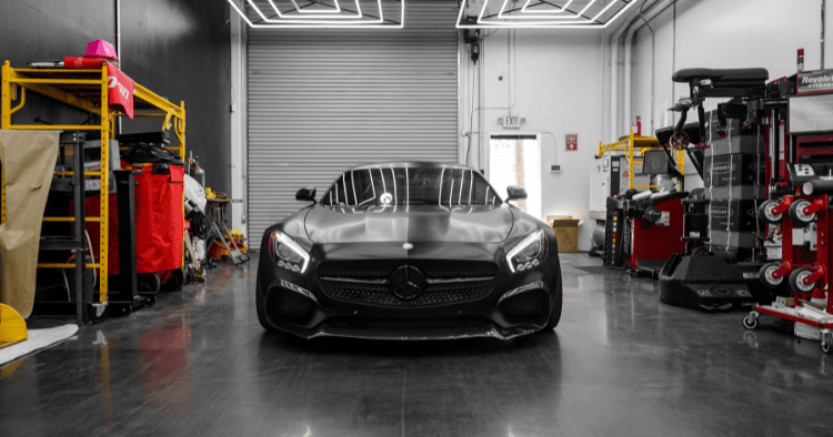 Black Mercedes AMG GT parked front-facing inside a garage with tools nearby.