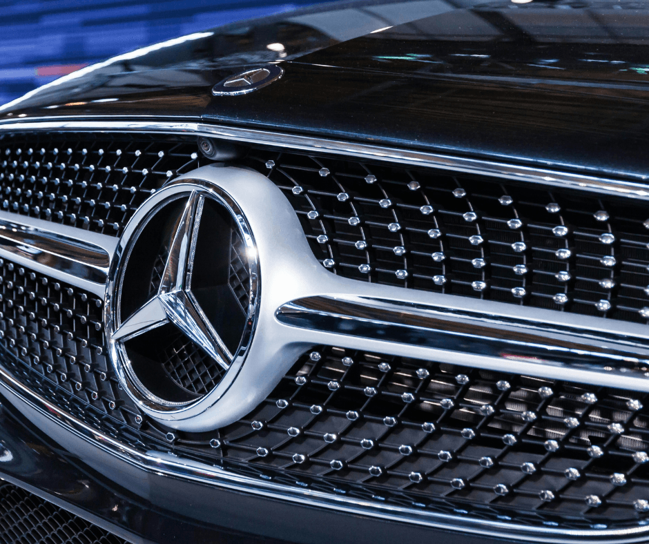 Interior view of a Mercedes-Benz steering wheel with integrated controls, flanked by a dual digital instrument cluster and infotainment screen displaying a SiriusXM radio menu.