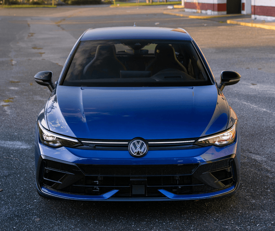 Front view of a Lapiz Blue Volkswagen Golf R parked in an open lot at golden hour, highlighting the aggressive front bumper design and LED light bar.
