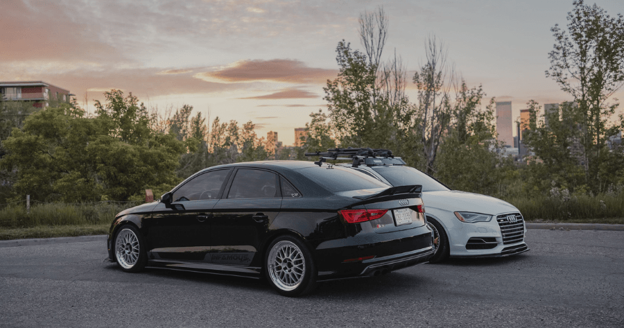 Black and white Audi A3 sedans parked together with a city skyline in the background